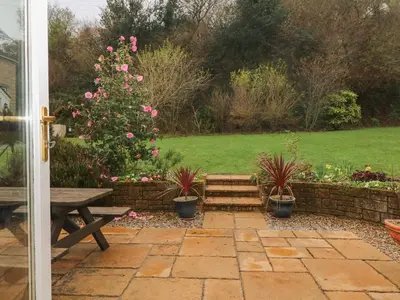a garden with a bench and a tree with pink flowers at Morton Cottage in Falmouth