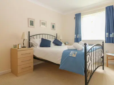 a bedroom with a bed and a window with blue curtains at Morton Cottage in Falmouth