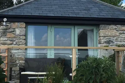 a glass window of a stone cottage with a bench at Skyber Barn, a rural retreat on Bodmin Moor in Liskeard