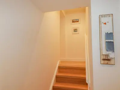 a hallway with stairs and paintings on the wall at Fistral Retreat in Newquay