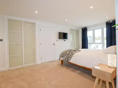 a bedroom with a bed and a tv on a wall at Fistral Retreat in Newquay