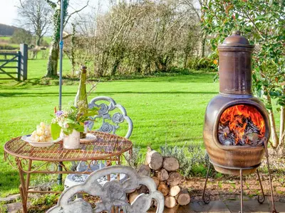 a table and a fire pit next to a table and chairs at The Observatory-Uk41754 in Lanreath