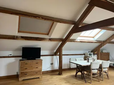 a dining room with a table with chairs and a television at The Old Stable - Flat 1 in Wadebridge
