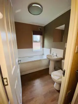 a bathroom with a toilet and a tub and a sink at Mariners Lodge in Saint Minver