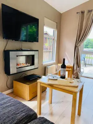 a living room with a table with a bottle of wine at Mariners Lodge in Saint Minver