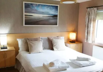 a bedroom with a white bed with two towels on it at Mariners Lodge in Saint Minver