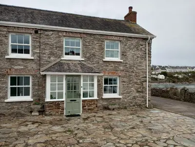 a brick house with white windows and a green door at Quayside in Porthscatho