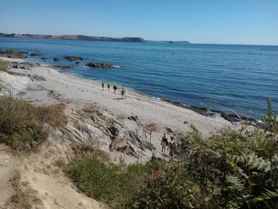a group of people walking on a beach near the water at Quayside in Porthscatho