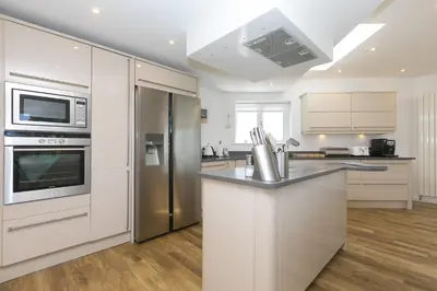 a kitchen with white cabinets and a stainless steel refrigerator at Portside in Carbis Bay