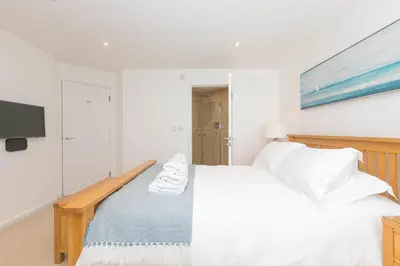 a white bedroom with a bed and a tv at Portside in Carbis Bay