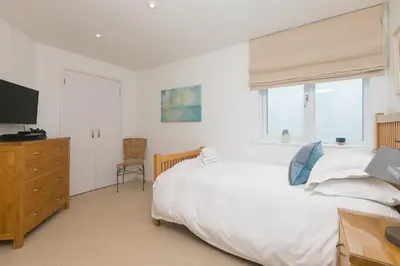 a bedroom with two beds and a tv and a dresser at Portside in Carbis Bay
