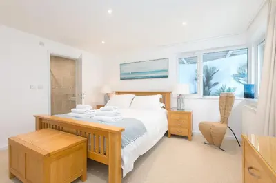 a white bedroom with a bed and a window at Portside in Carbis Bay