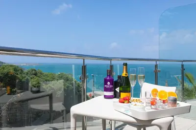 a table with wine bottles and glasses on a balcony at Portside in Carbis Bay