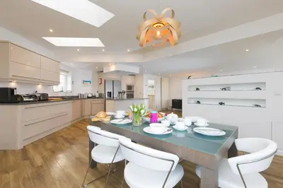 a kitchen with a dining table and white chairs at Starboard in Carbis Bay