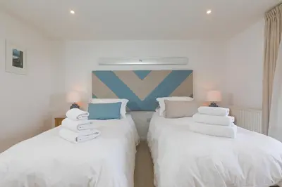 two beds with towels on them in a room at Starboard in Carbis Bay