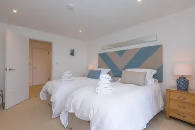 two beds in a bedroom with white sheets at Starboard in Carbis Bay