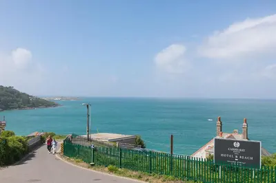 people walking down a path next to the ocean at Starboard in Carbis Bay