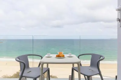 a table and two chairs with a table and a beach at Turquarze in Carbis Bay