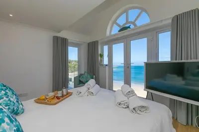 a bedroom with a large bed with a view of the ocean at Turquarze in Carbis Bay
