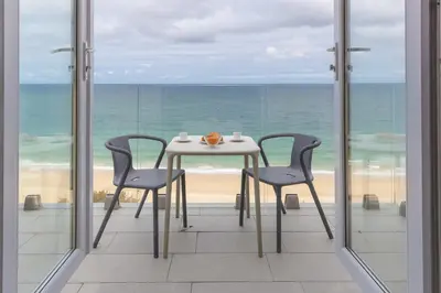 a table and two chairs on a balcony with the ocean at Turquarze in Carbis Bay