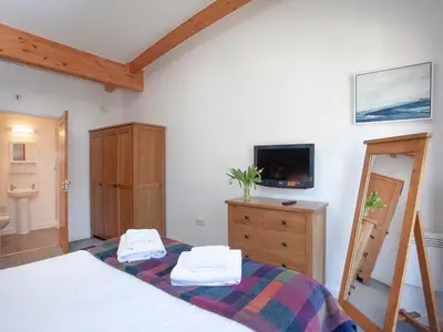 a bedroom with a bed and a dresser and a tv at Trebisken - Cottage in Porthtowan