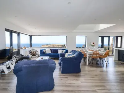 a living room with blue couches and a table at Camelot in Tintagel