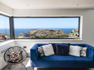 a blue couch in a room with a large window at Camelot in Tintagel