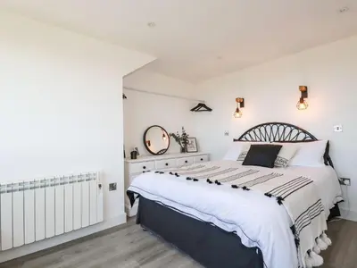 a bedroom with a large bed and a mirror at Camelot in Tintagel