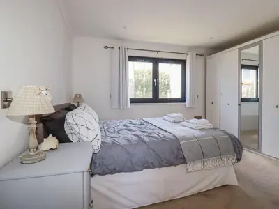 a white bedroom with a bed and a window at Camelot in Tintagel