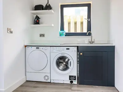 a laundry room with a washing machine and a sink at Camelot in Tintagel