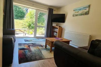 a living room with a couch and a table and a window at Cornish Point in Newquay