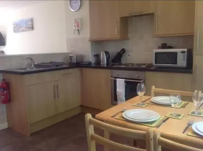 a kitchen with a wooden table with plates and wine glasses at Cornish Point in Newquay