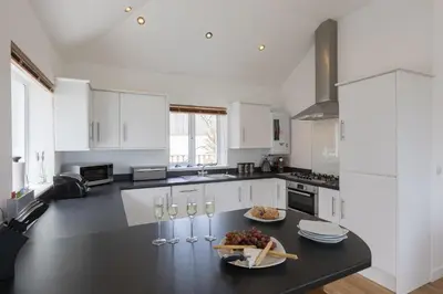 a kitchen with white cabinets and a black counter top at Beachcomber in Carbis Bay