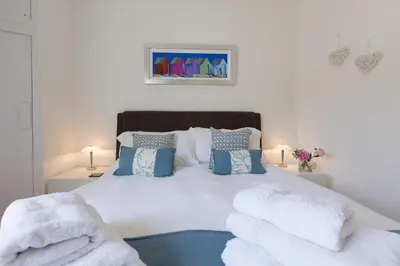 a bedroom with a large white bed with blue pillows at Beachcomber in Carbis Bay