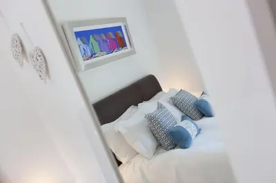 a bedroom with a bed with pillows and a mirror at Beachcomber in Carbis Bay