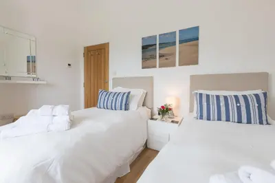 two beds in a room with white walls at Beachcomber in Carbis Bay