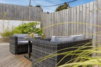 a patio with a table and chairs and a fence at Beachcomber in Carbis Bay