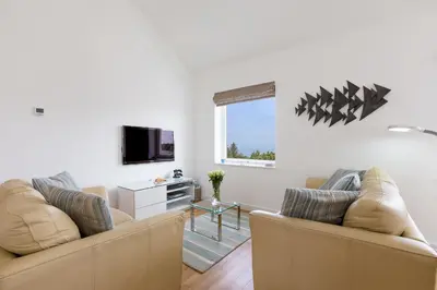 a living room with two couches and a tv at Beachcomber in Carbis Bay