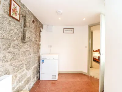 a kitchen with a stone wall and a refrigerator at Larch Barn in Helston
