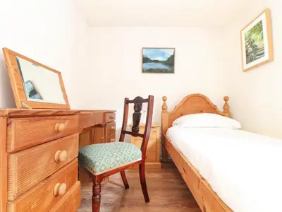 a bedroom with a bed and a dresser and a chair at Larch Barn in Helston