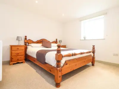 a bedroom with a wooden bed and a window at Larch Barn in Helston