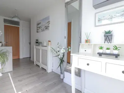 a white bathroom with a mirror and a white dresser at Palm View in Newquay