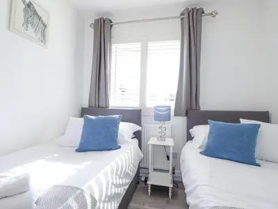two beds in a bedroom with blue and white pillows at Palm View in Newquay