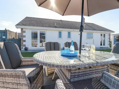 a table and chairs with an umbrella on a patio at Palm View in Newquay