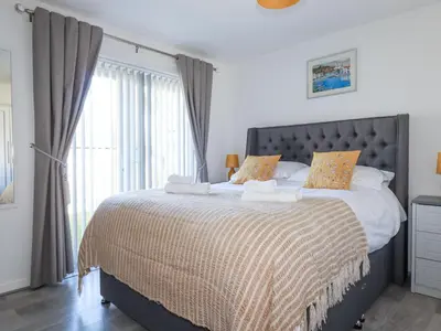 a bedroom with a large bed with a large window at Palm View in Newquay