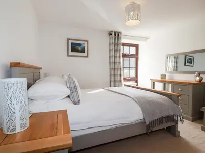 a bedroom with a bed and a desk and a window at Great Meadow Barn in Newquay
