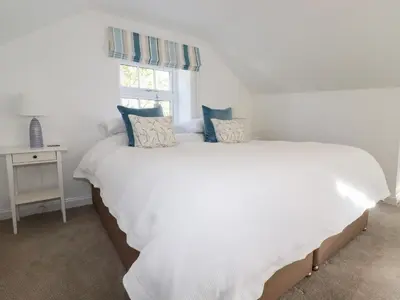 a white bed in a room with a window at Great Meadow Barn in Newquay
