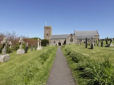 a church with a path leading to a cemetery at Great Meadow Barn in Newquay