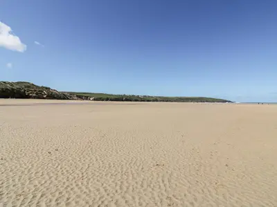 a sandy beach with footprints in the sand at Great Meadow Barn in Newquay
