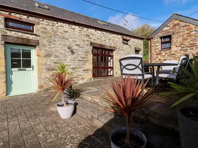 a patio with a table and chairs and plants at Great Meadow Barn in Newquay